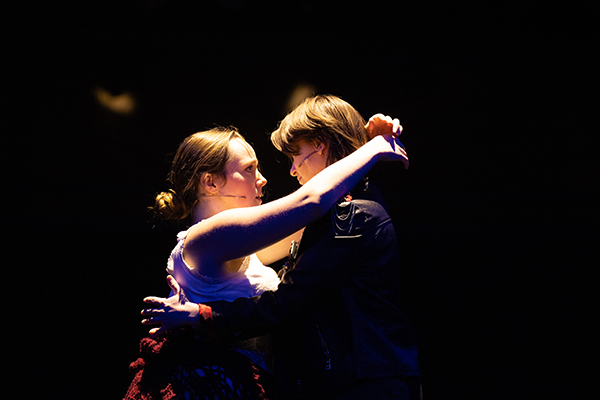 Two people slow dancing while light illuminates them.