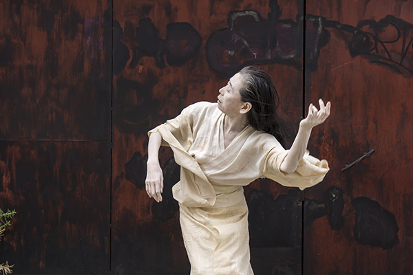 Older Asian woman dress in white mid-dance.