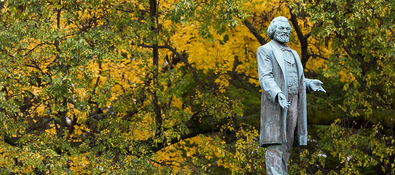 Frederick Douglass statue against the wooded backdrop of Highland Park.