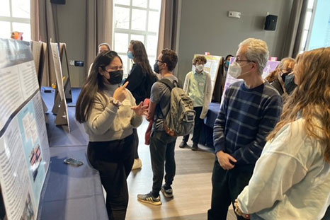 A student at the poster session with attendees.