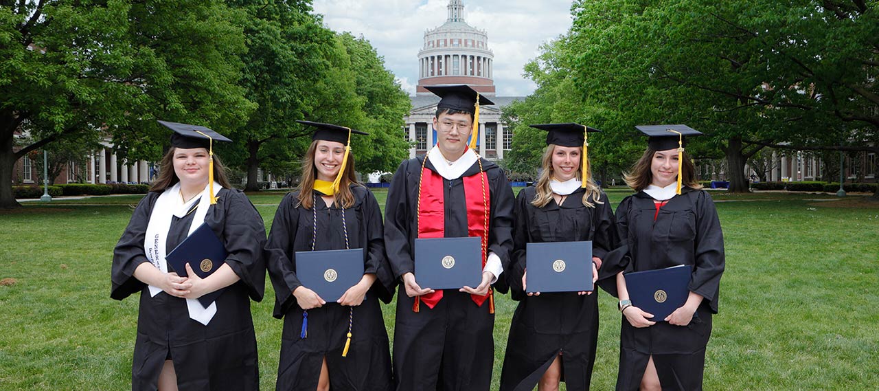 A group of ASL graduates from the class of 2021 posing for a photo on the Eastman Quad with their diplomas.