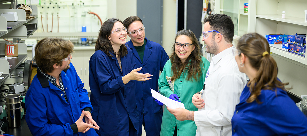 Students laughing and talking in a lab setting.