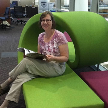 Sue Cardinal sitting in the library reading a book.