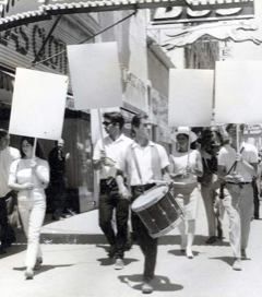 A group of people marching in the street with blank placards.
