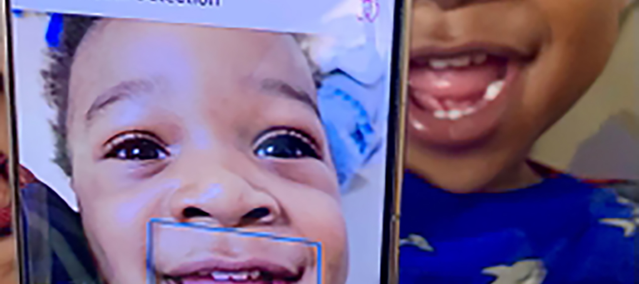 A cell phone capturing the image of a smiling baby.