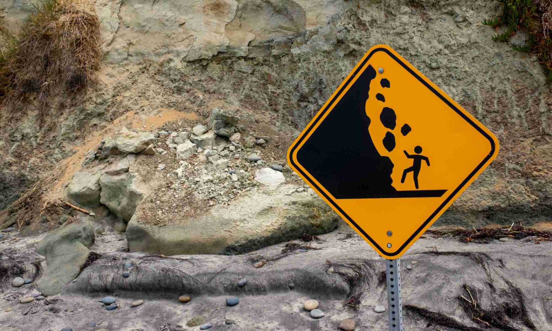 Falling rocks warning sign in front of rocks and boulders of various sizes along a mountainside to illustrate the idea of granular systems.