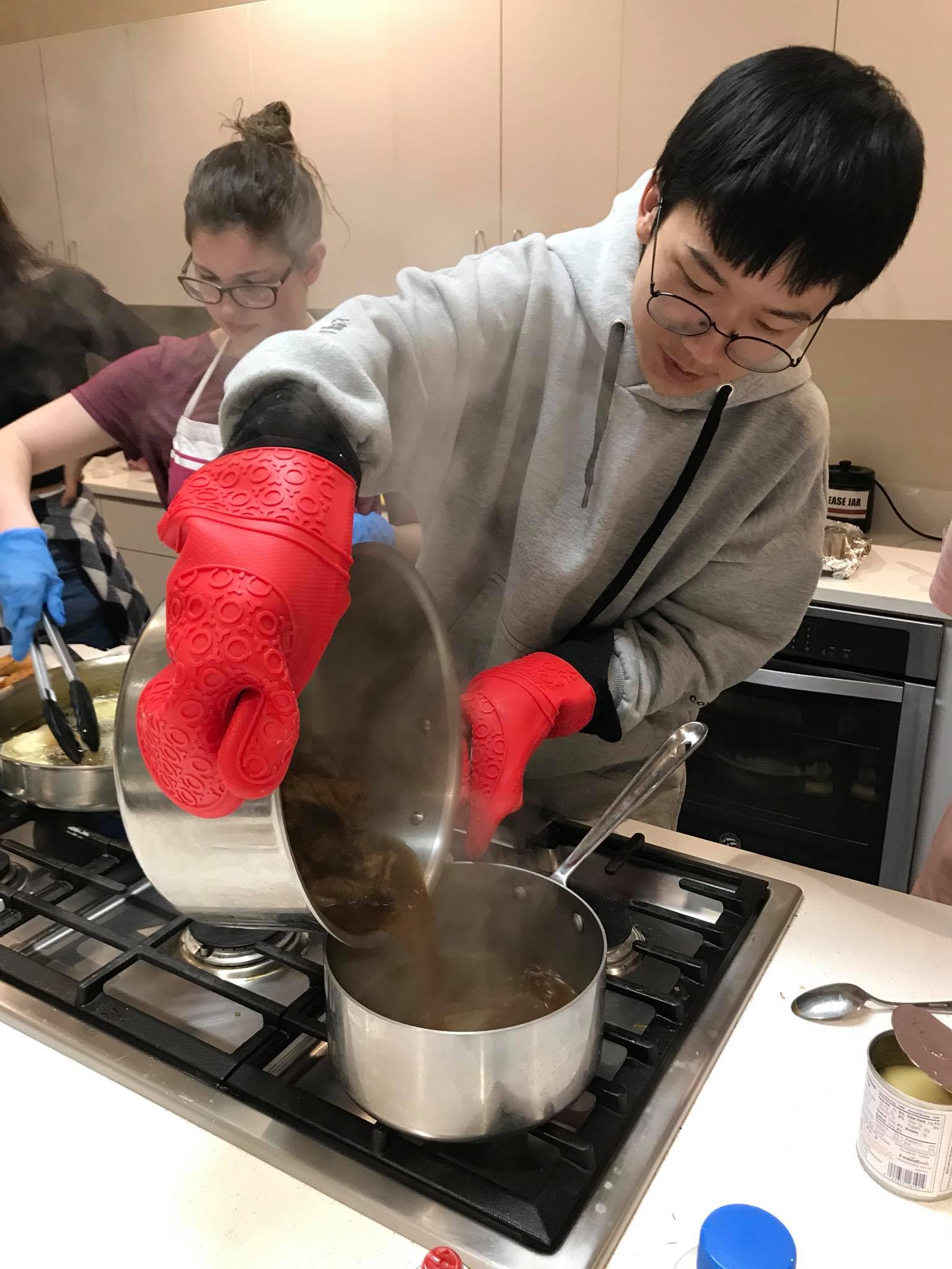 Student pouring a pot of liquid into another pot