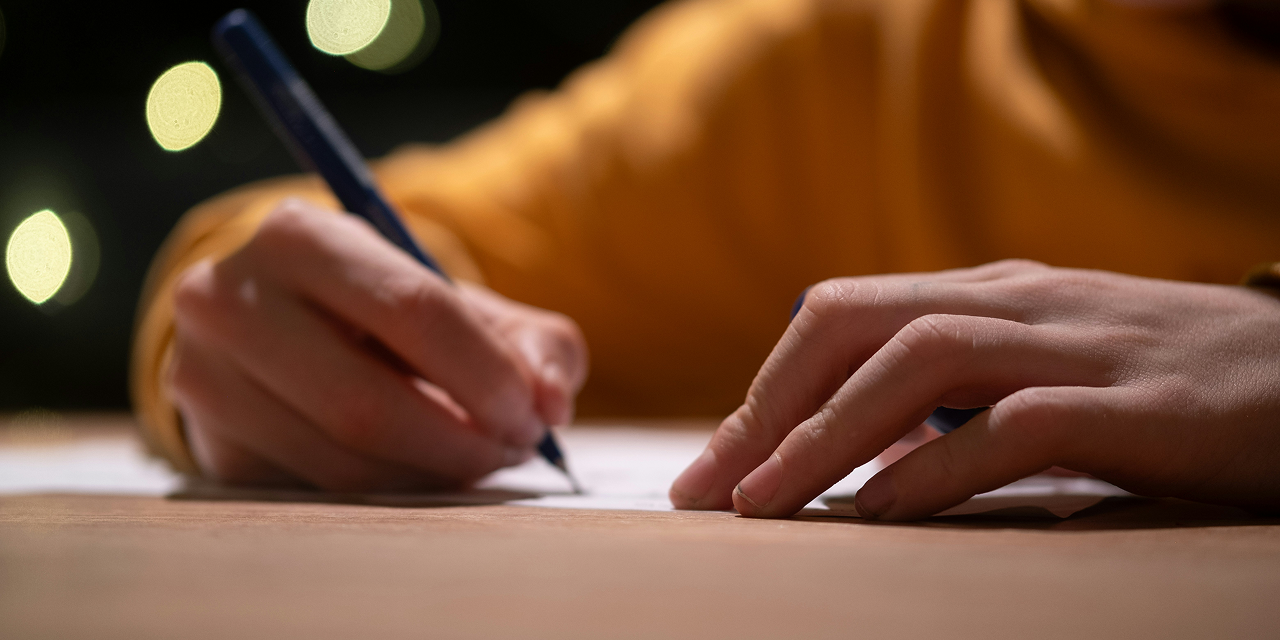A close up of a hand writing in a notebook.