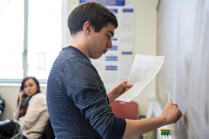 A student writing on a blackboard in class.