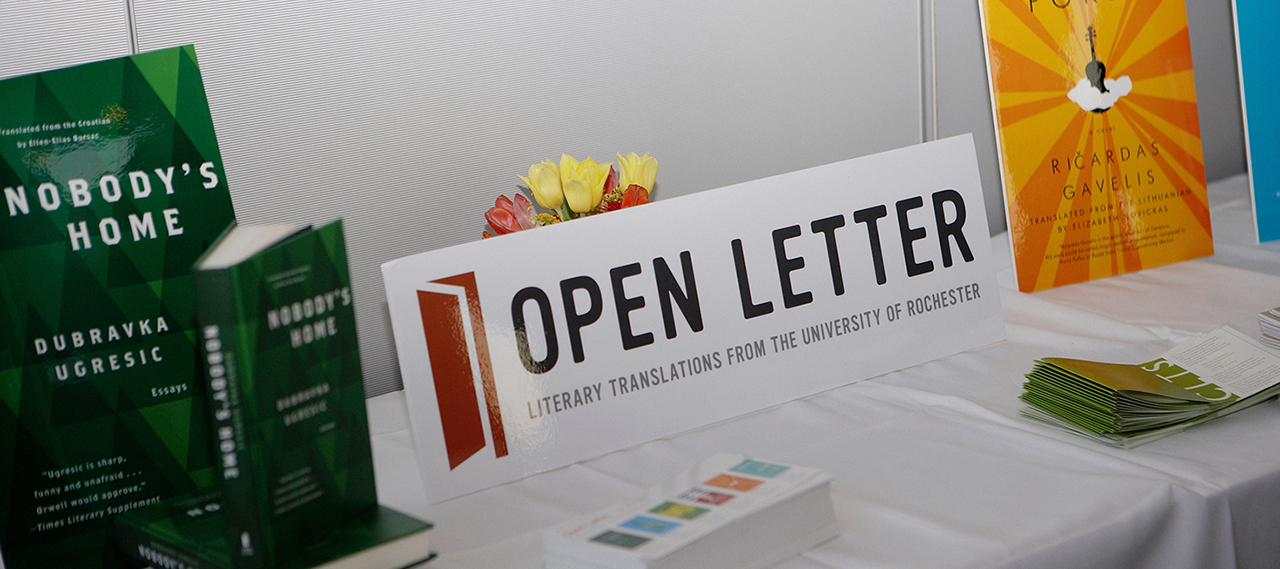 A table containing a stack of books and a sign for Open Letter Press.