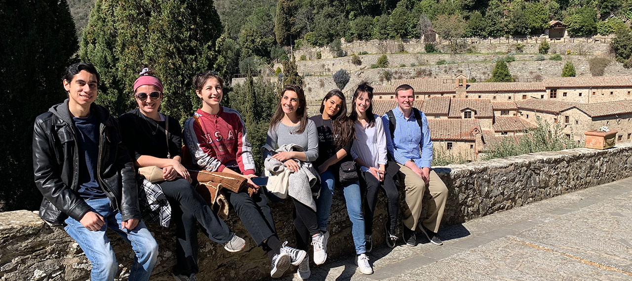 A group of students sitting on a wall in Cortona.