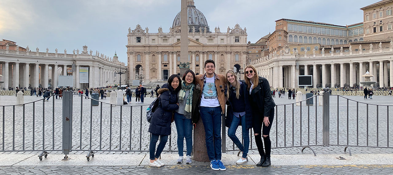 A group of students pose for a photo in a piazza.