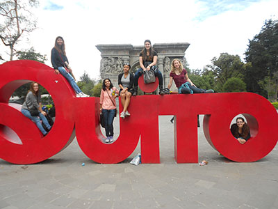 Students posing on large letters that spell Quito.