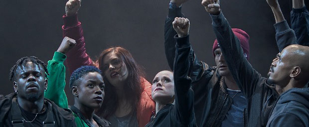 A still image from the movie of a group of people with the fists raised in the air.
