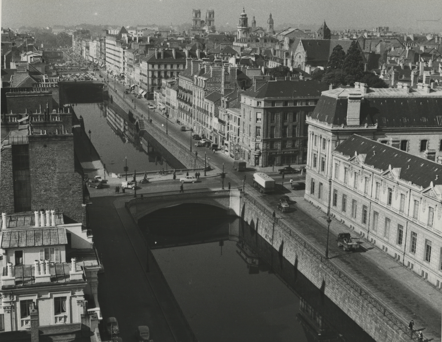 black and white photo of a river with bridges crossing it and buildings on both sides