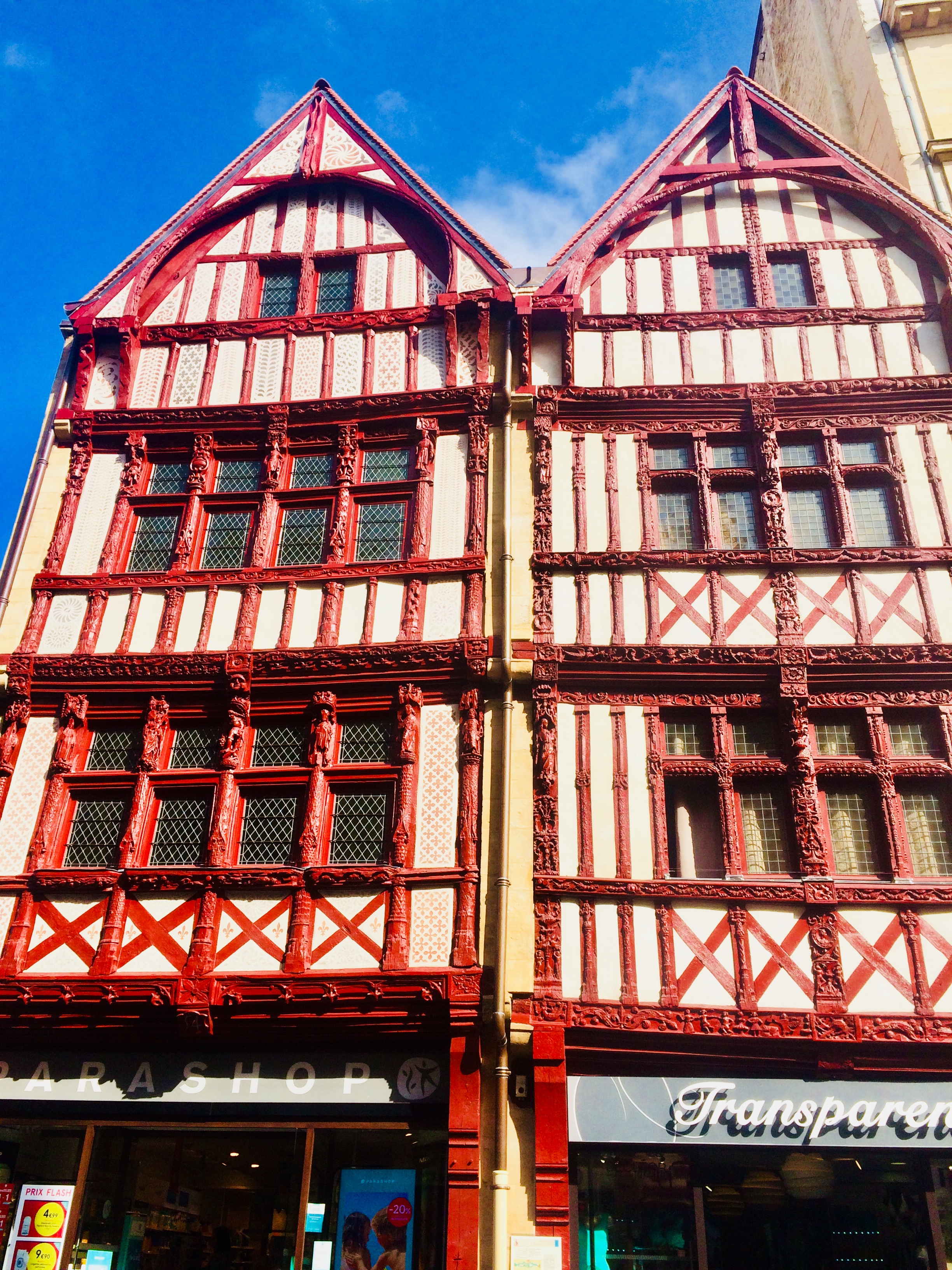 twin old buildings with red woodwork around the windows and decorating the front