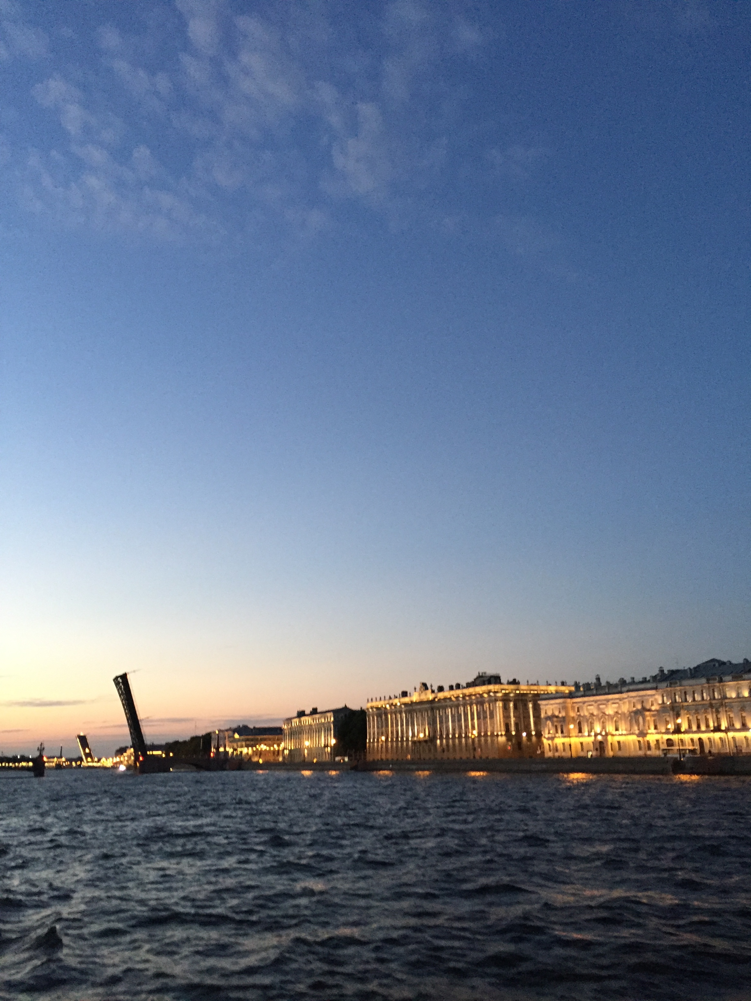 view of buildings lit up at twilight, across the neva river 