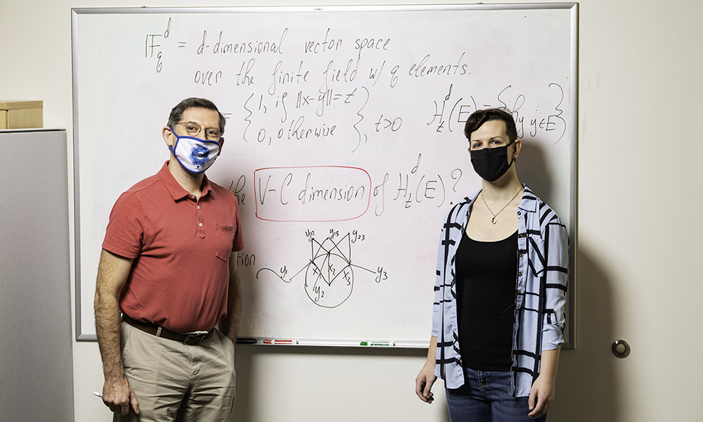 Professor Iosevich standing in front of a whiteboard with a student.