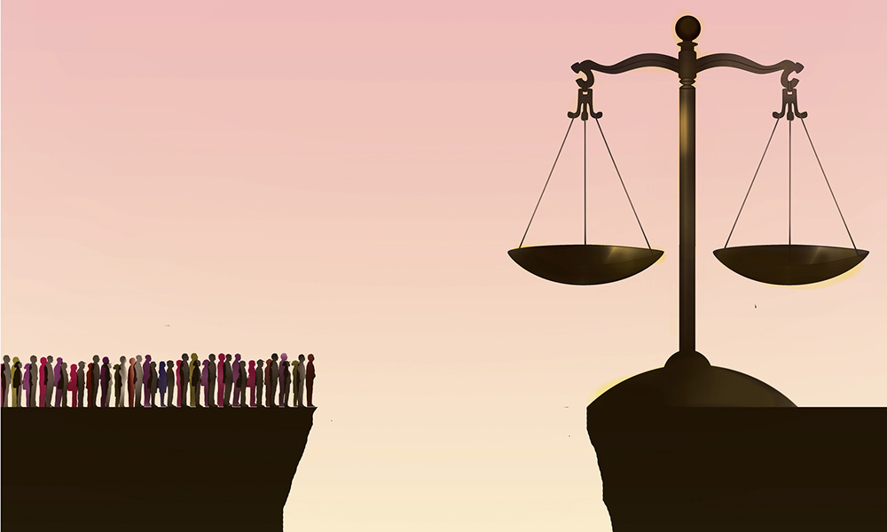 A graphic on a chasm with a group of people on one side and the scales of justice on the other.
