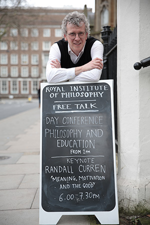 Professor Curren leaning on sidewalk sign