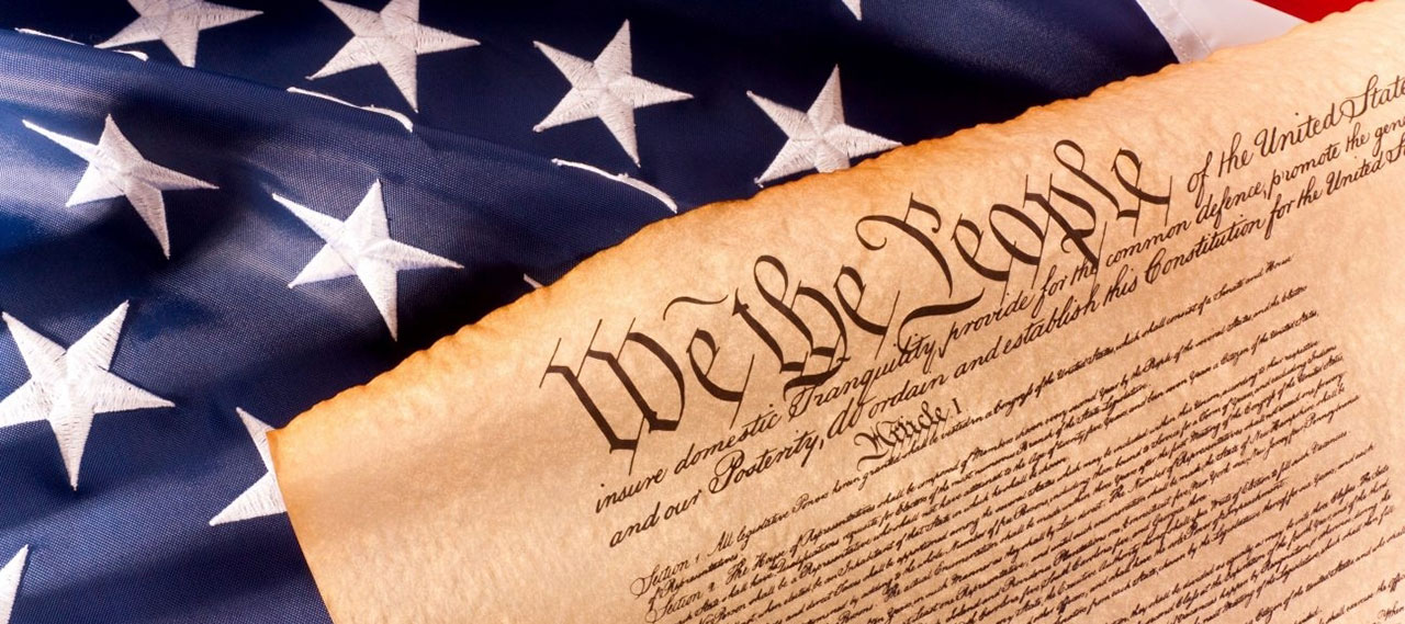 A cropped copy of the constitution overlaying an American flag.