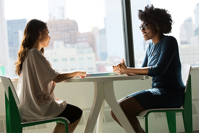 Two people sitting at a table in front of a window.