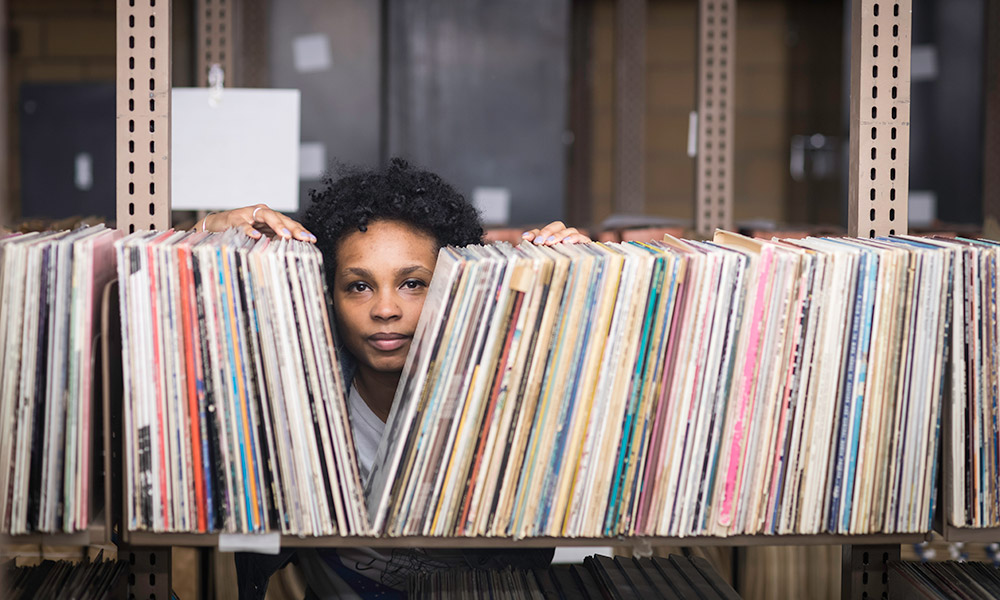 Ash Arder looking out from behind a shelf of records.