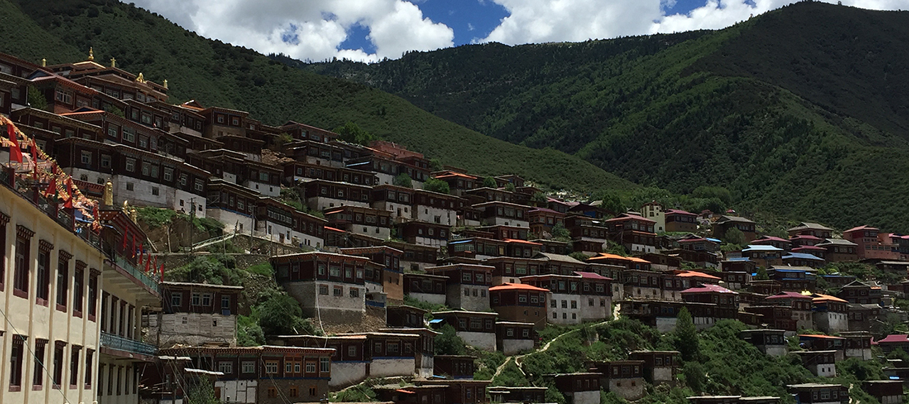 View of a hillside with dwellings and the sky above.