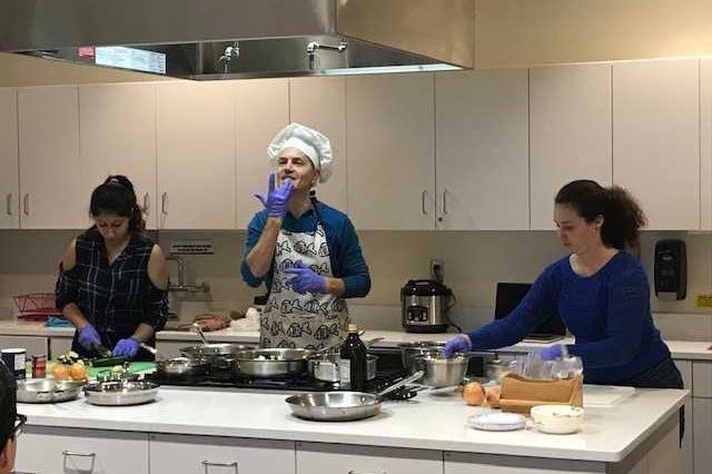 Three people cooking in hats and aprons.