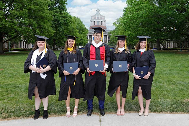 A group of students pose in their caps and gowns.