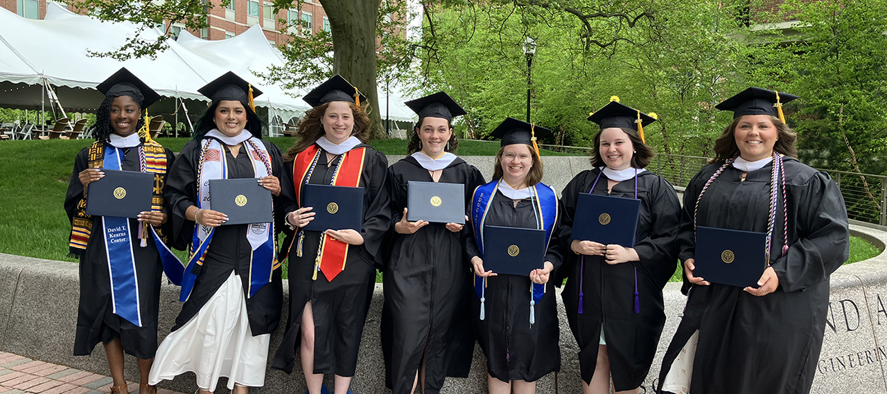 A group of ASL graduates from the class of 2023 posing for a photo on the Hajim Quad with their diplomas.