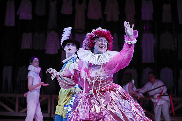 Three students in costume performing on stage.