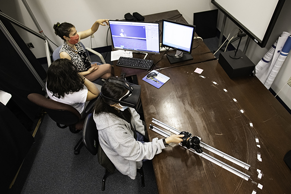 Three students conducting an experiment with equipment and a computer.