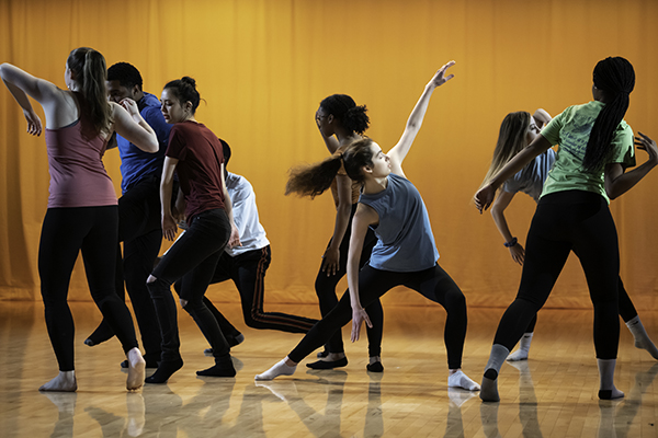A group of students on stage posing in different positions.