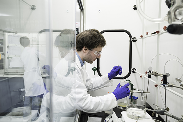 A student wearing a lab coat working in a lab.