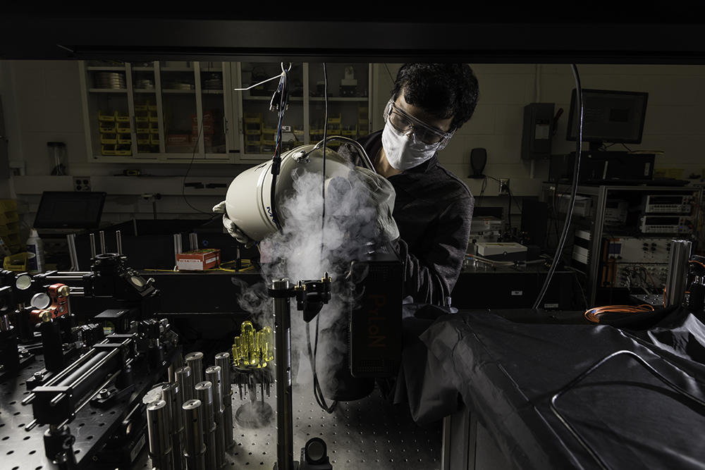 A student pouring a liquid into a container in a lab.