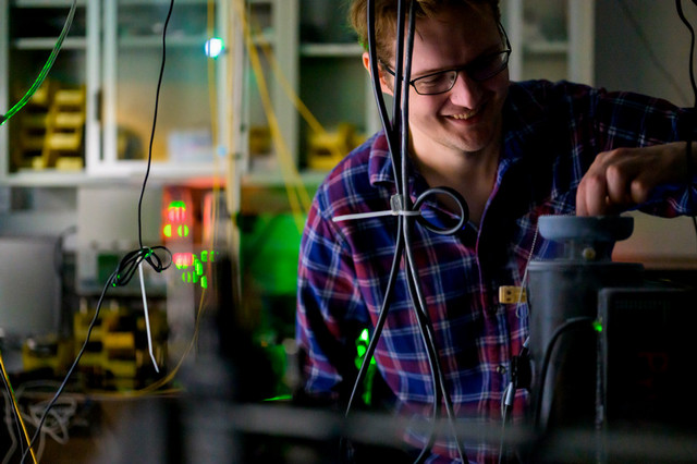 A PhD student smiles while working with samples in a lab.