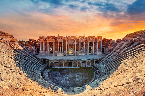 A stylized rendering of an ancient outdoor arena with a columned building at one end.