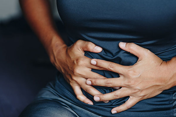 woman's hands grabbing her abdomen due to endometriosis symptoms