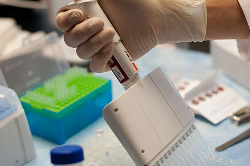 A hand emptying a syringe into a container.