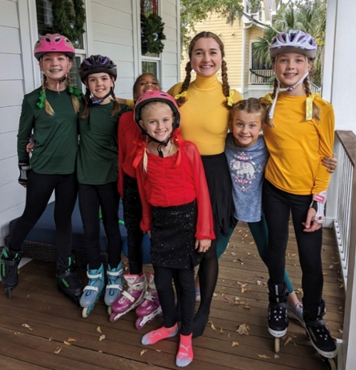 A group of children in rollerblading gear smiling at the camera.