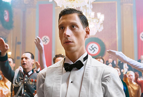 A still image from the movie of a man in a white tuxedo.