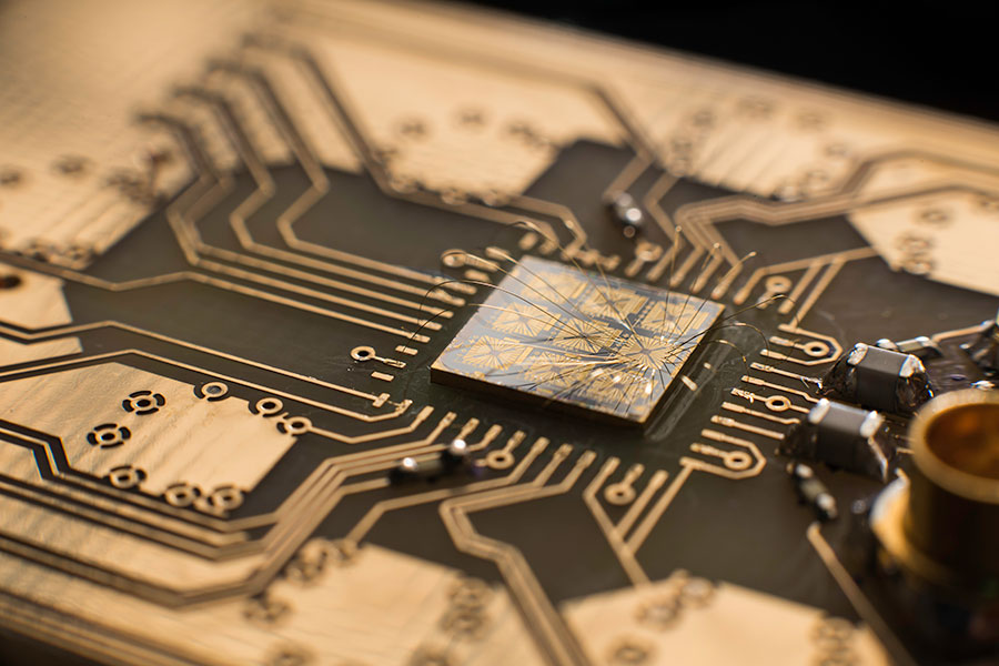 A quantum processor semiconductor chip is seen connected to a circuit board.