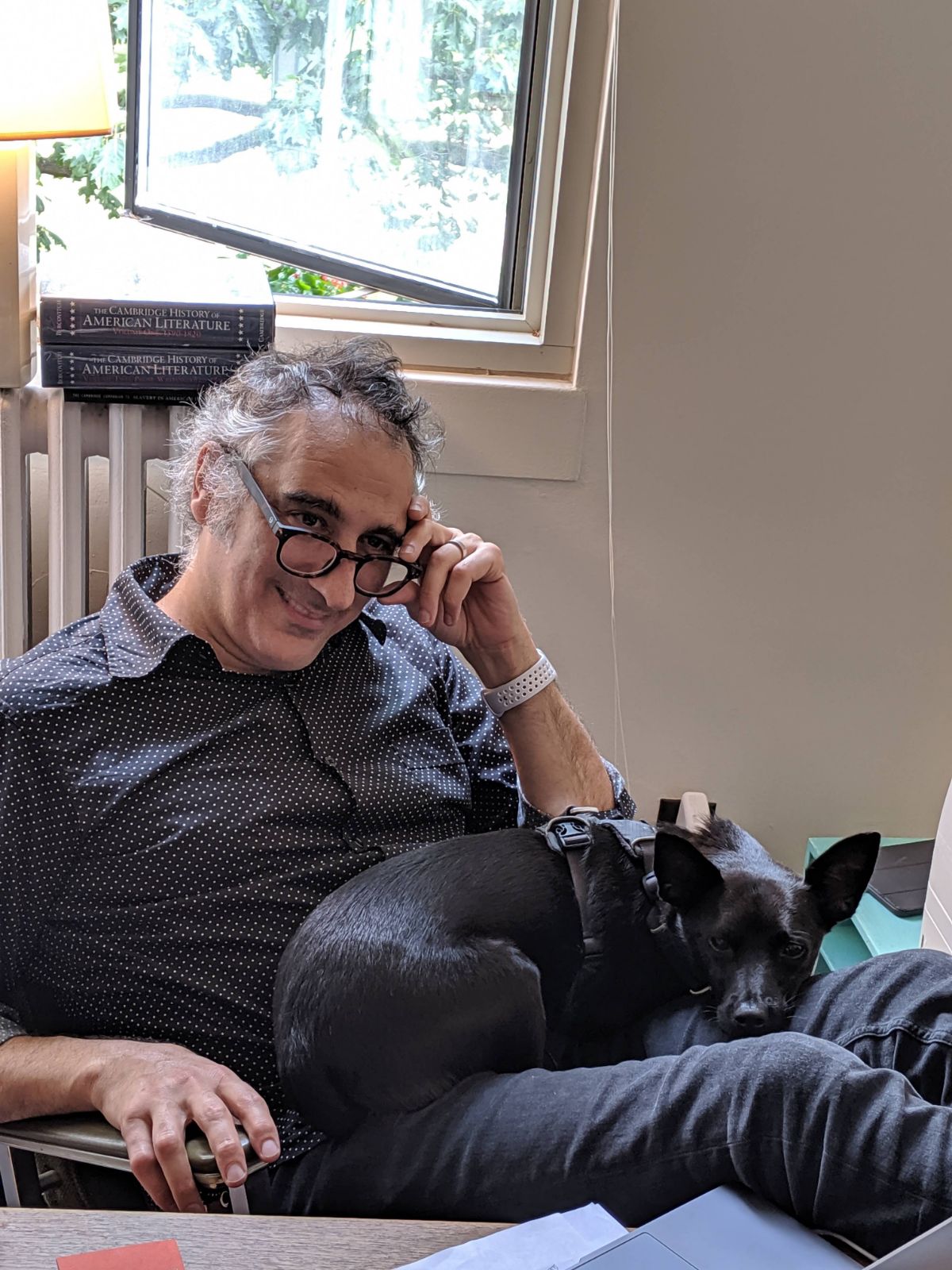 Professor Tawil sitting in his office with his feet on his desk and his dog in his lap.