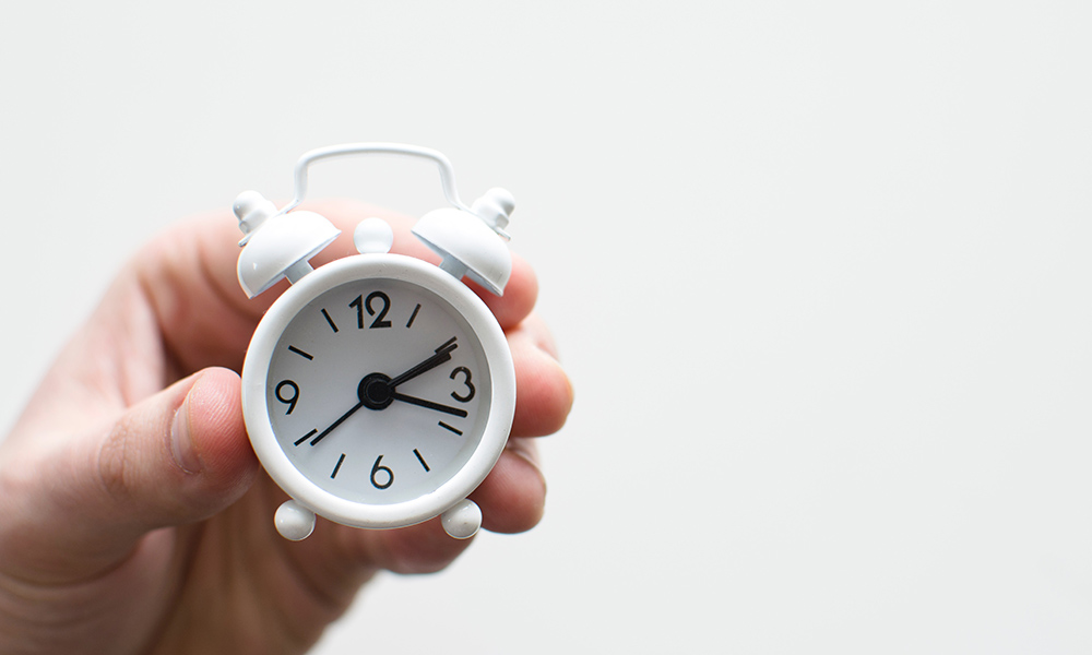 Hand holding a small alarm clock