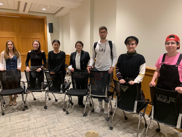 students stand with embroidered chairs