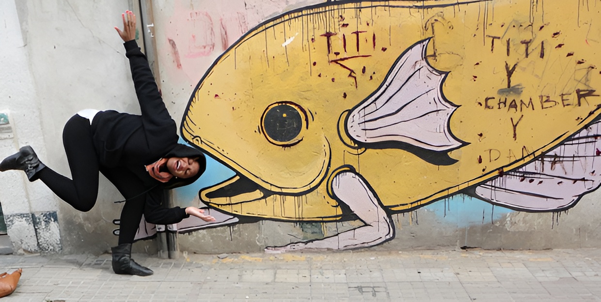 A person pretending to get eaten by a graffiti fish.