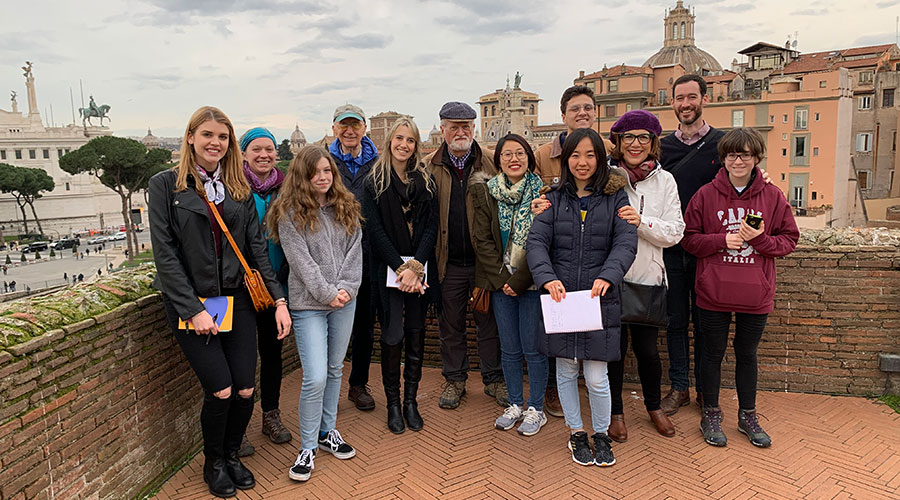 A group of students and instructors pose for the camera with a view of Arezzo in the background.