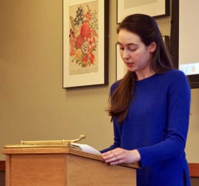 o a young woman in a royal blue shirt presenting at a podium