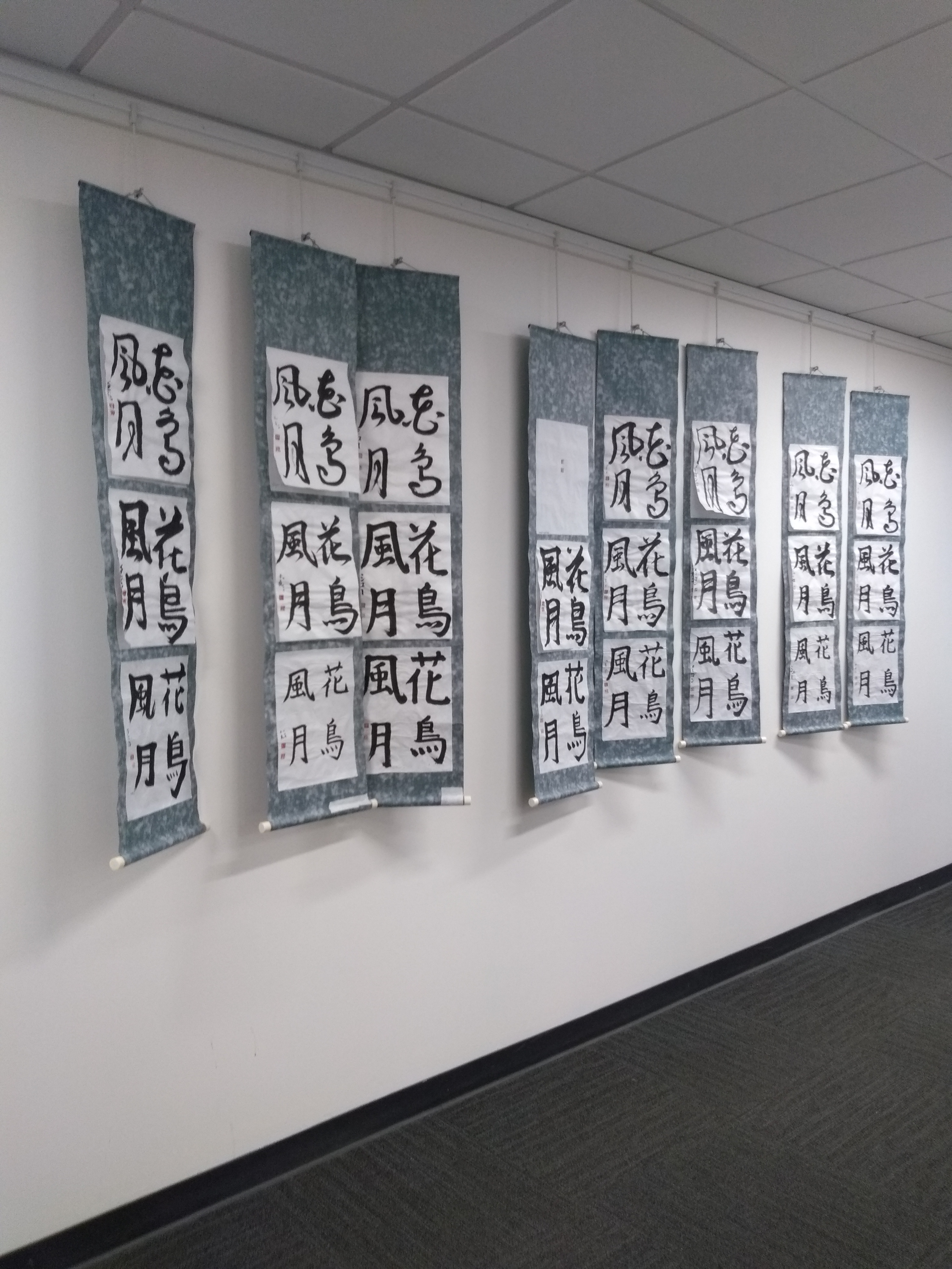 o row of hanging calligraphy scrolls, each with three pieces displayed vertically